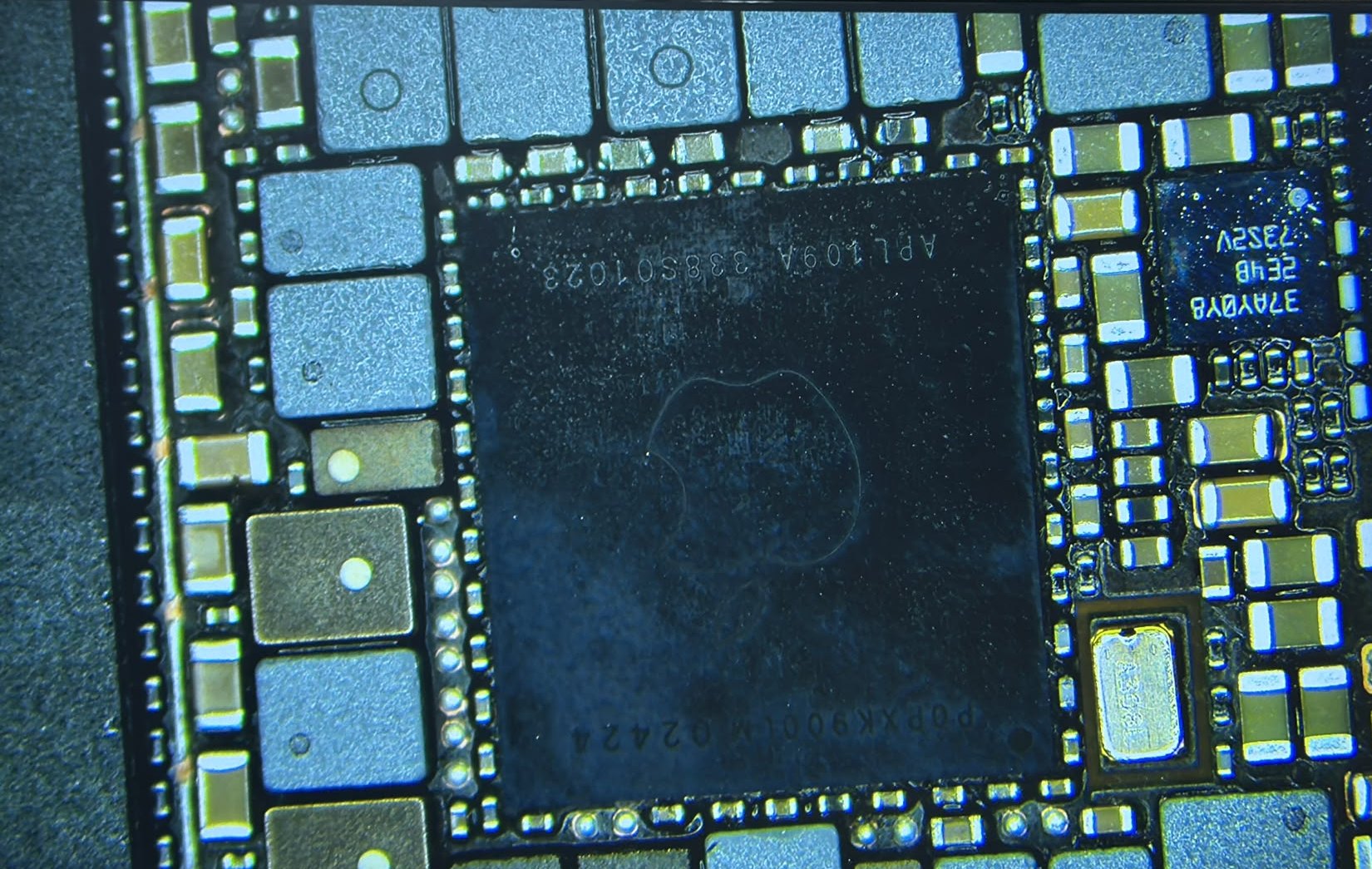Mikroskopaufnahme des Prozessors und der umliegenden Bauteile auf der gereinigten Hauptplatine eines iPhone 15 Pro